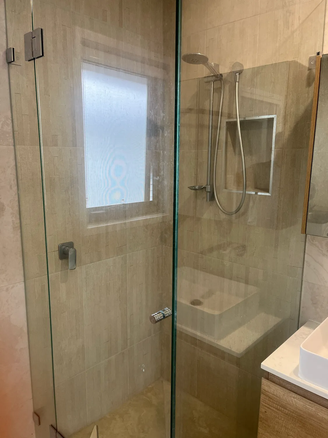 Frameless shower glass with mineral deposits before cleaning
