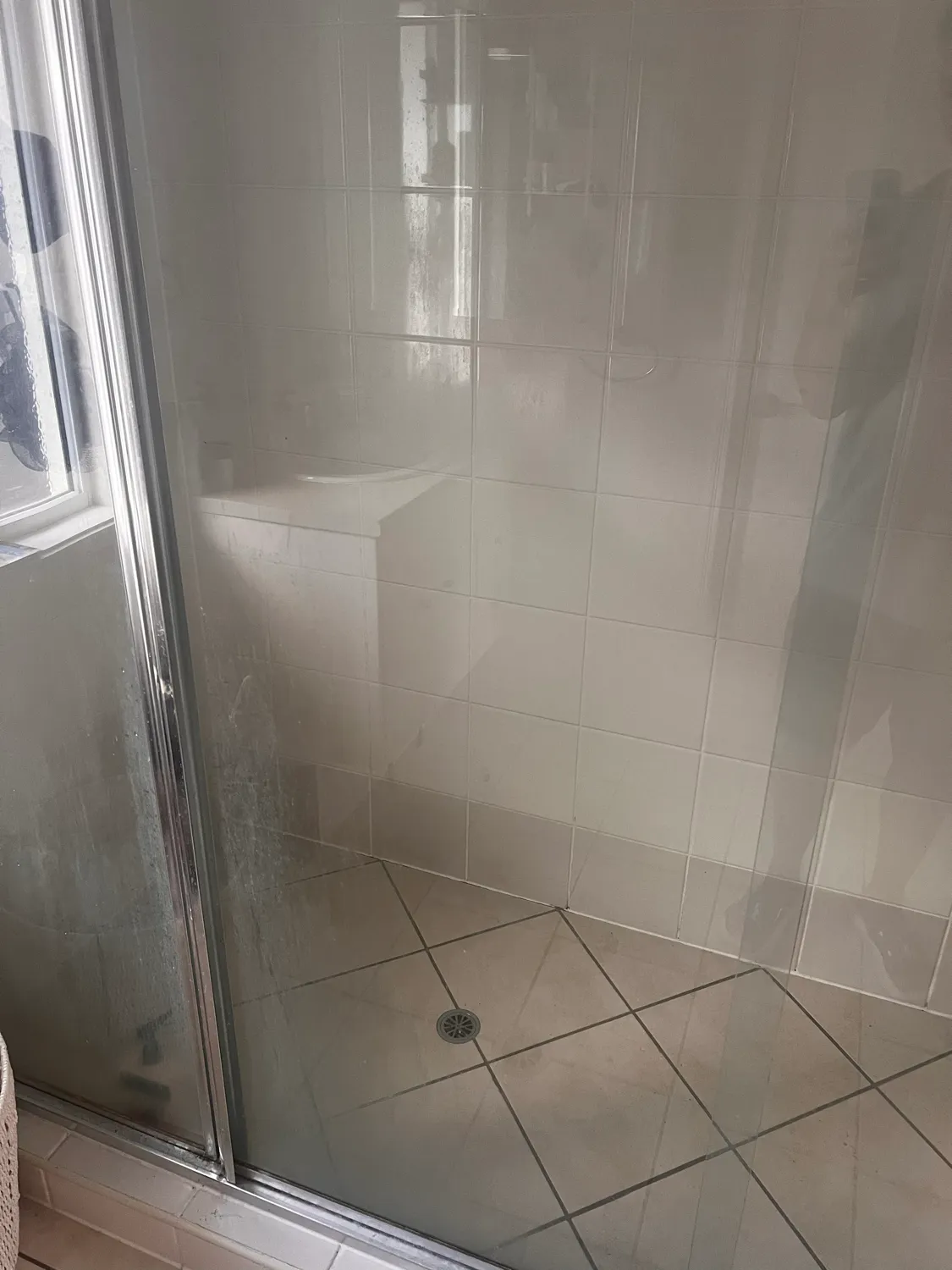 Shower glass door with soap scum before cleaning