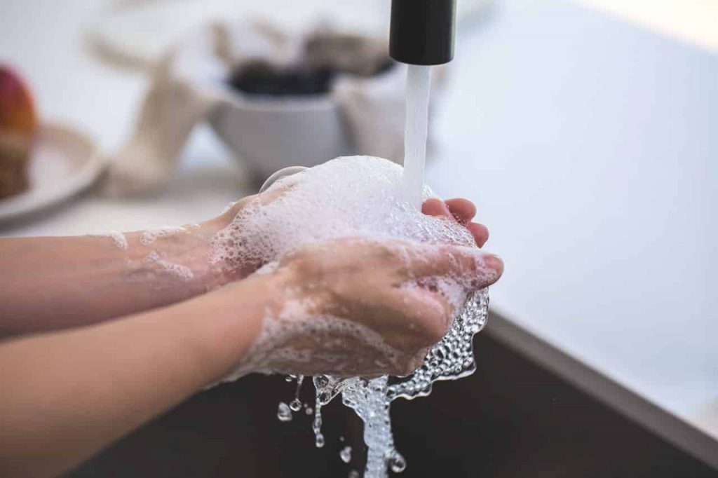 washing hands under a sink with soap
