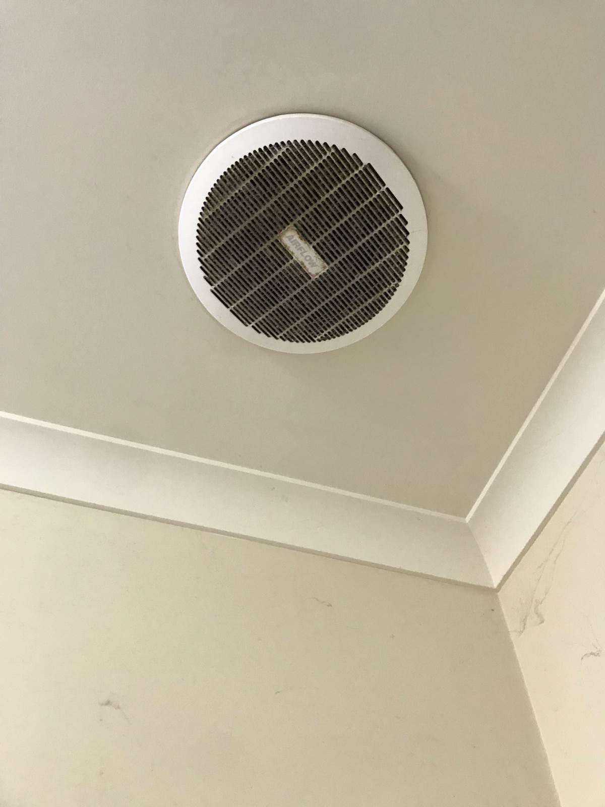 Ceiling exhaust fan grille with dust and grime buildup before cleaning
