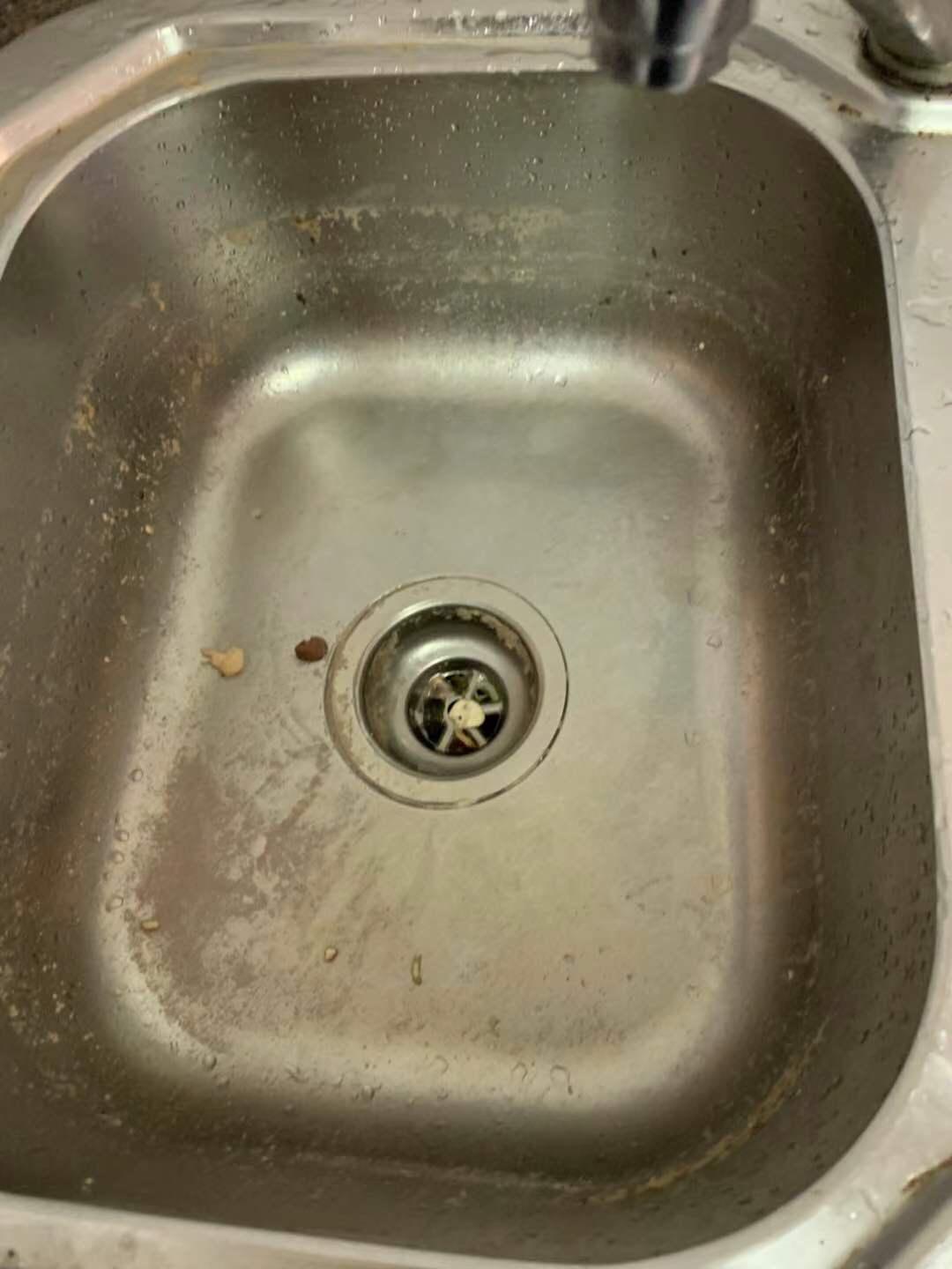 Kitchen sink with grease buildup and food residue before cleaning